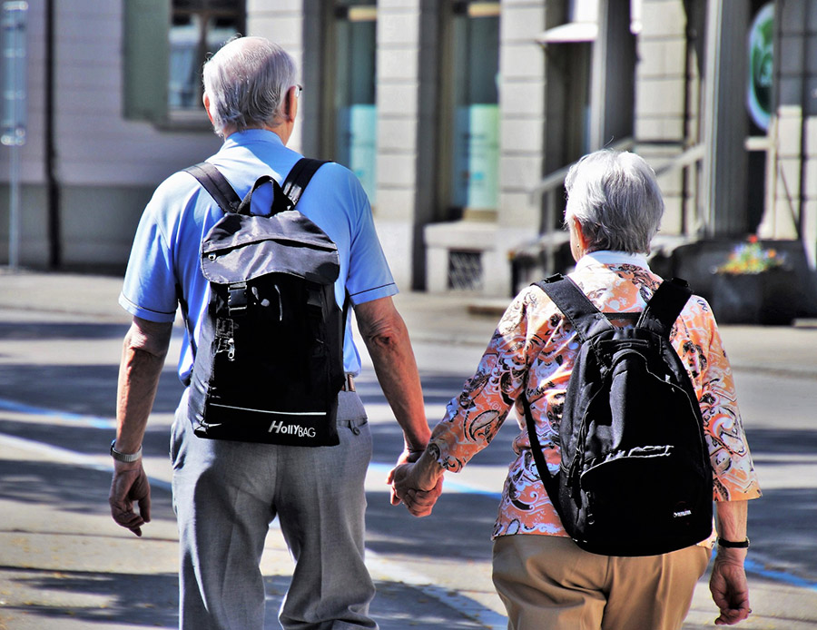 Dos personas mayores disfrutando de un paseo por un paisaje encantador, tomados de la mano. Esta imagen representa la alegría y la conexión que experimenta la tercera edad a través de los viajes personalizados que ofrece Plenitud Viajera.